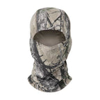 Full-face tactical balaclava in tan and grey forest tree camouflage pattern with a single open eye and nose cutout.
