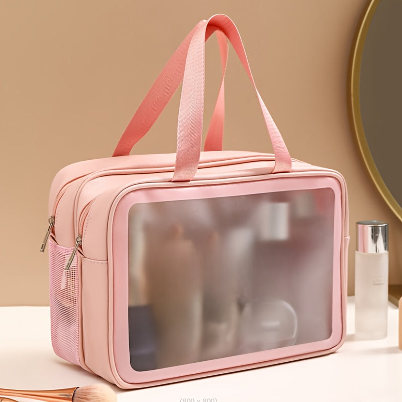 Pastel pink travel makeup bag with a clear front window, top carry handles, and side mesh pockets.