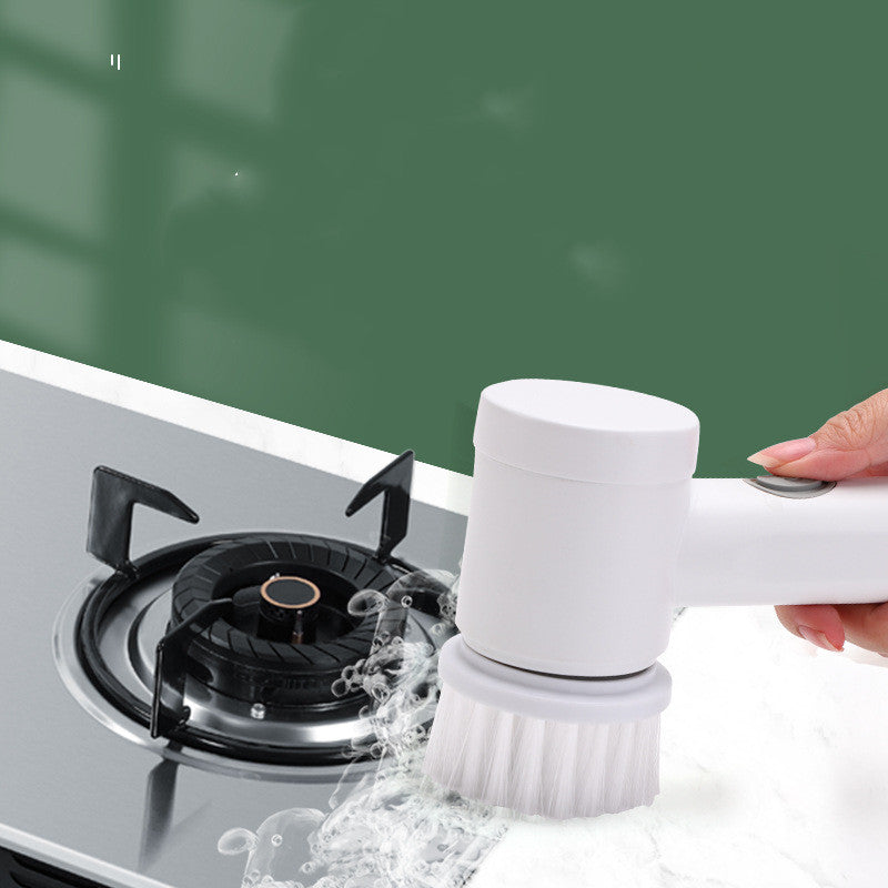 A white, handheld electric cleaning brush scrubbing a stovetop, featuring a cylindrical head and white nylon bristles.
