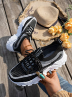 Black and grey breathable flyknit mesh sneakers with chunky white outsoles, lace-up design, and patterned pull tabs.