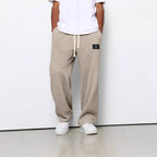 Beige waffle-knit straight-leg trousers with a drawstring waist, side pockets, and a small black patch label.