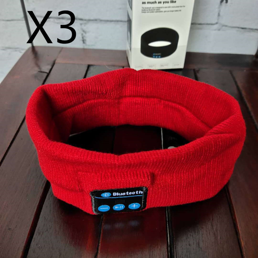 Red knit Bluetooth sports headband with a control panel on the front, placed on a wooden table with product box.