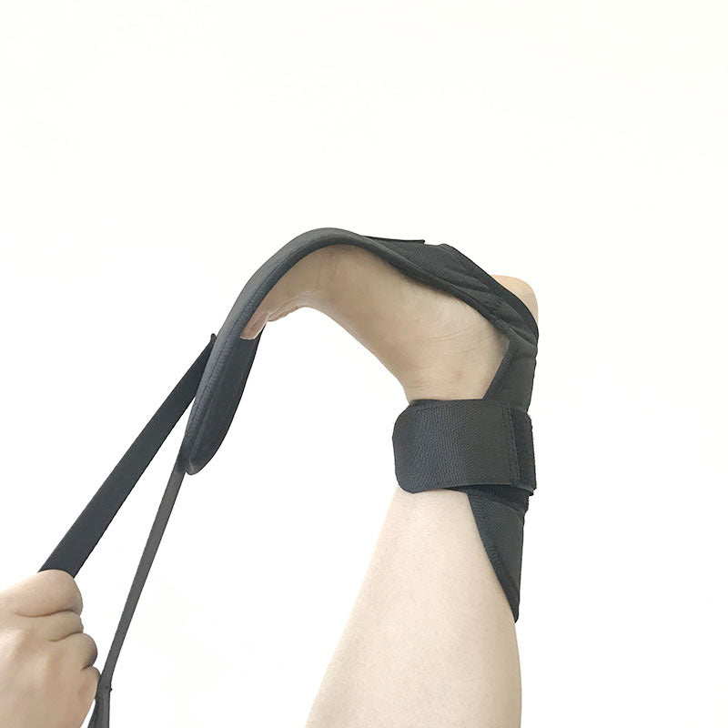 Black fabric rehabilitation foot strap with ankle brace, used for stretching and foot drop correction on a human foot.