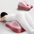 A pink, ergonomic, two-tone foam cushion used to elevate the hips for face-down reclining and comfort.