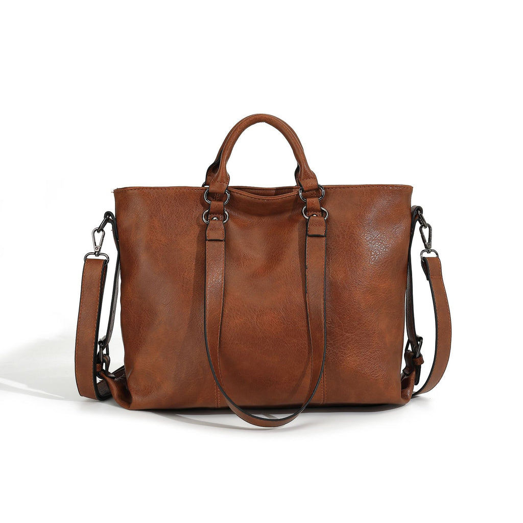 Large brown soft leather tote bag with top handles, detachable shoulder strap, and dark hardware on white background.