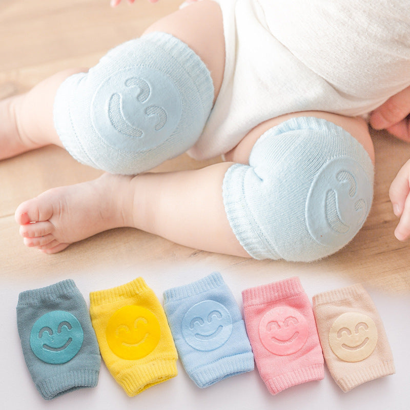 Baby wearing light blue terry knee pads with smiley faces, with a variety of colored pairs shown below.