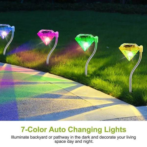 Four diamond-shaped, color-changing solar LED lights on curved stakes illuminating a garden path.
