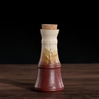 Ceramic wine decanter with a cork stopper, featuring a gradient finish from dark red to cream and embossed leaf design.