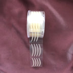A roll of 600 beige, arched adhesive eyelid stickers for creating a double eyelid on a dark purple fabric background.