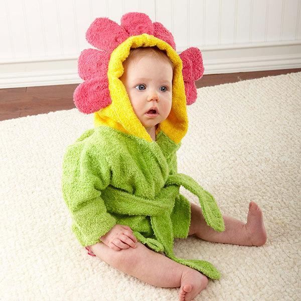 Baby wearing a soft, lime green cotton bathrobe with a yellow and pink flower-shaped hood sitting on a white rug.