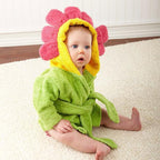 Baby wearing a soft, lime green cotton bathrobe with a yellow and pink flower-shaped hood sitting on a white rug.