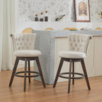 Two beige, velvet-upholstered swivel bar stools with button-tufted backs, nailhead trim, and dark wood legs.