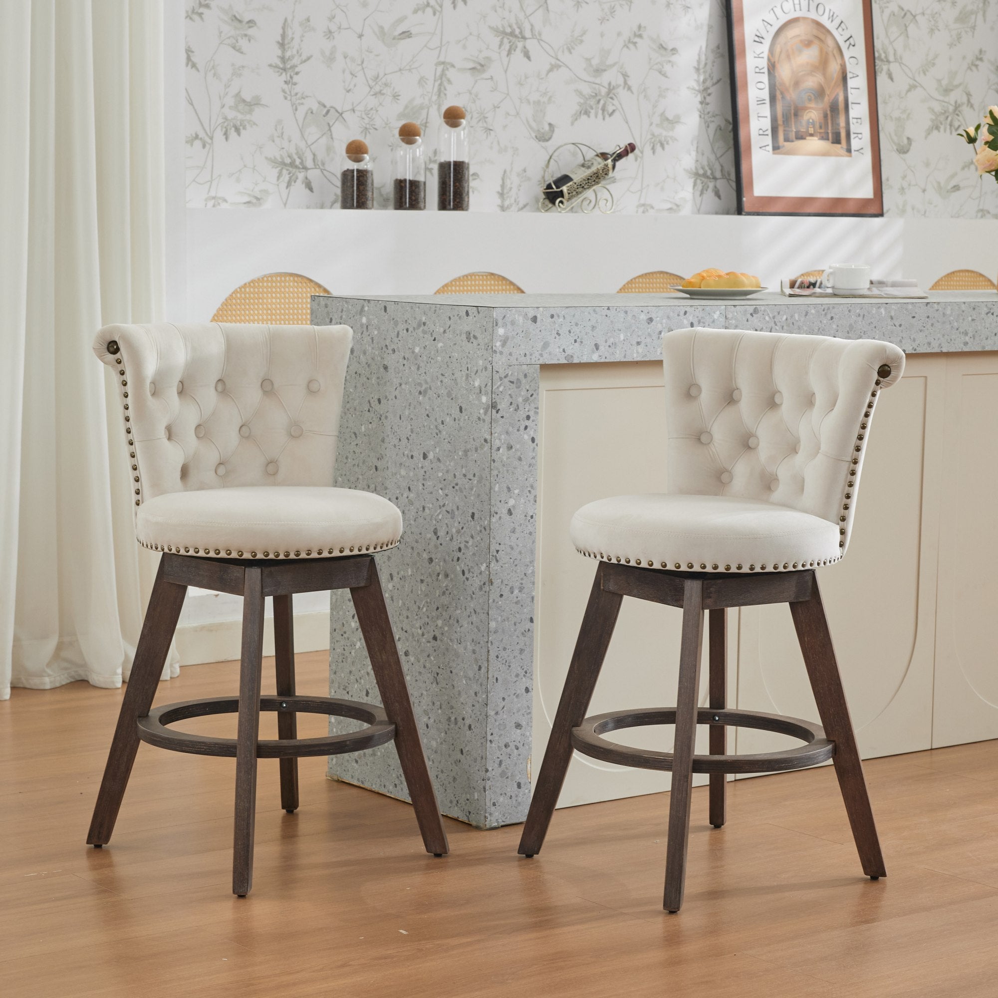 Two beige, velvet-upholstered swivel bar stools with button-tufted backs, nailhead trim, and dark wood legs.