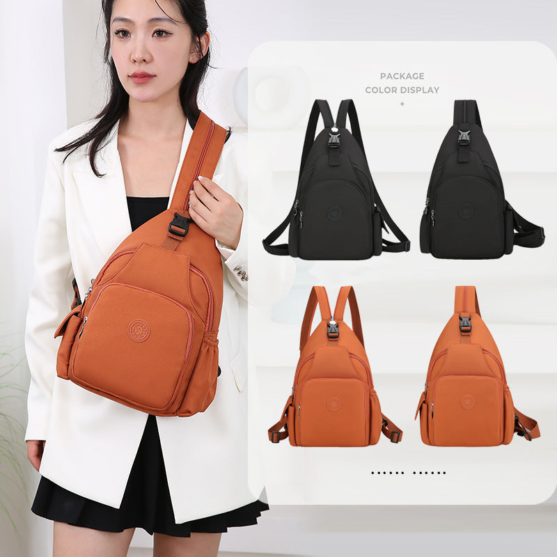 Woman wears a waterproof orange crossbody backpack with side pockets and buckles. Available in black and orange options.