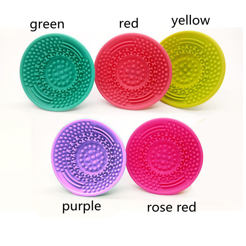 Five colorful, silicone circular makeup brush cleaning pads with textured surfaces, labeled by color on a white background.