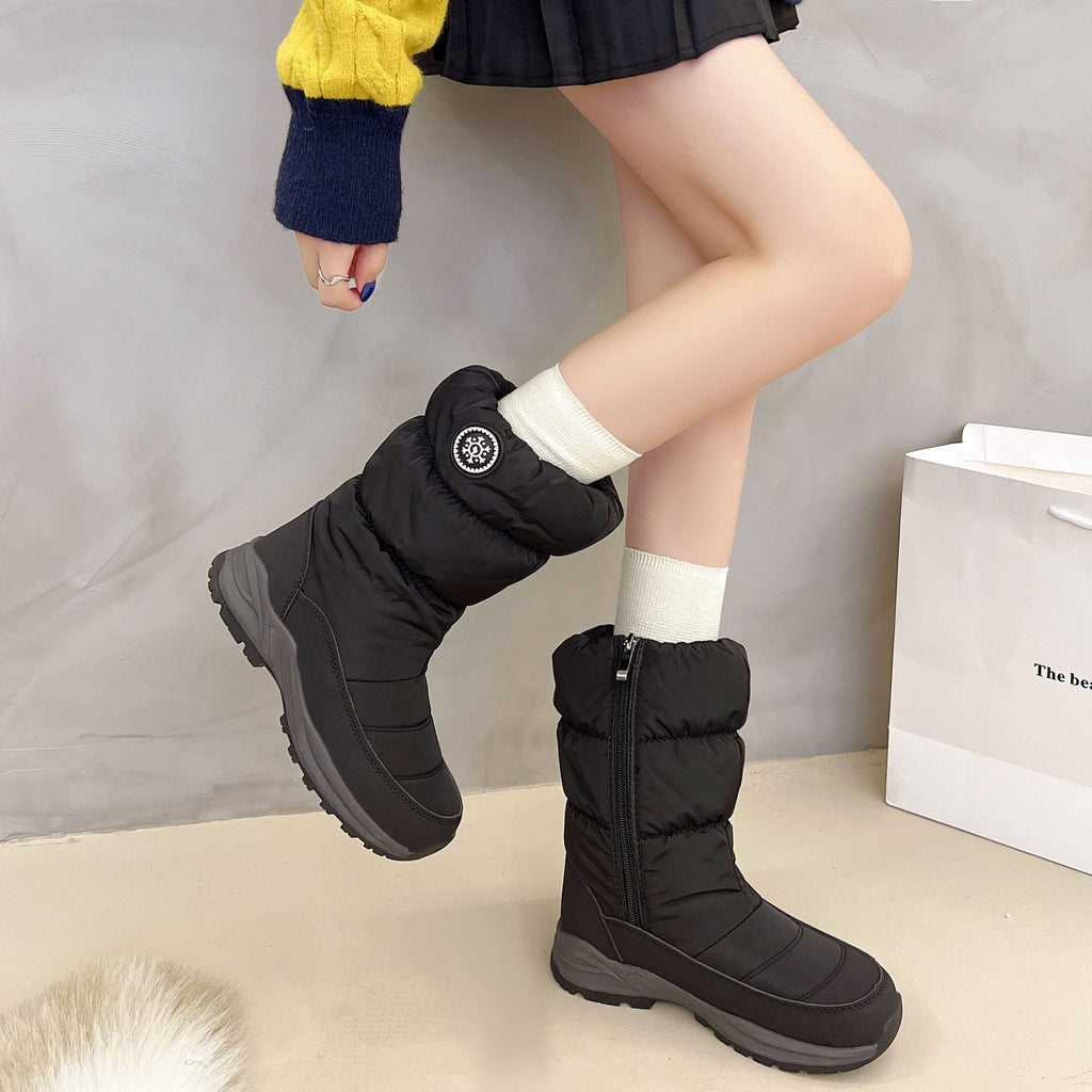 Black, mid-calf, quilted cotton snow boots with side zippers, circular logo, and thick gray lug soles on a model.