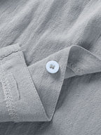 Close-up of a light gray, textured cotton-blend casual shirt with a single matching button on the collar placket.
