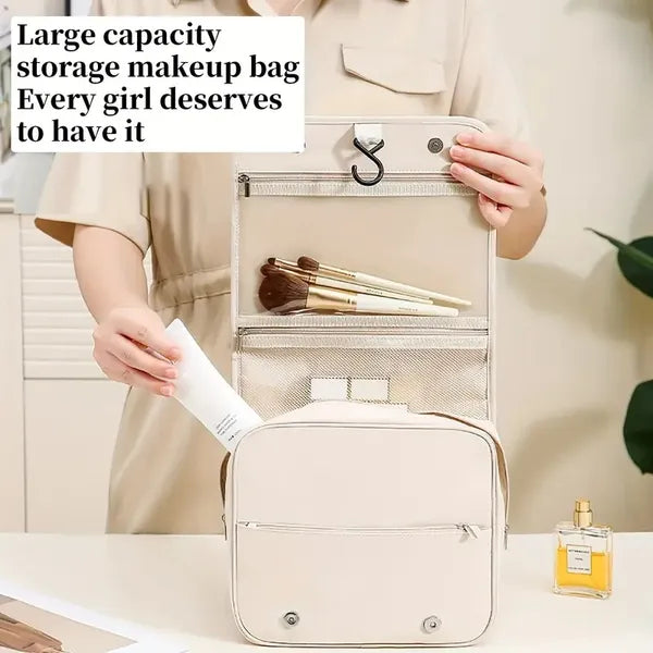 Beige hanging travel cosmetic bag with a hook, internal mesh pockets for brushes, and a front zip compartment.