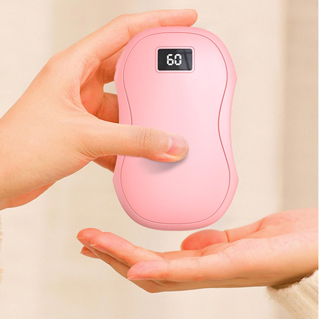 A person holds a smooth, pink, pebble-shaped electric hand warmer with a digital display showing "60" degrees.