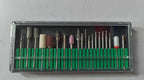 A clear plastic case holds various metal drill bits and sanding tips, organized in a green tray.