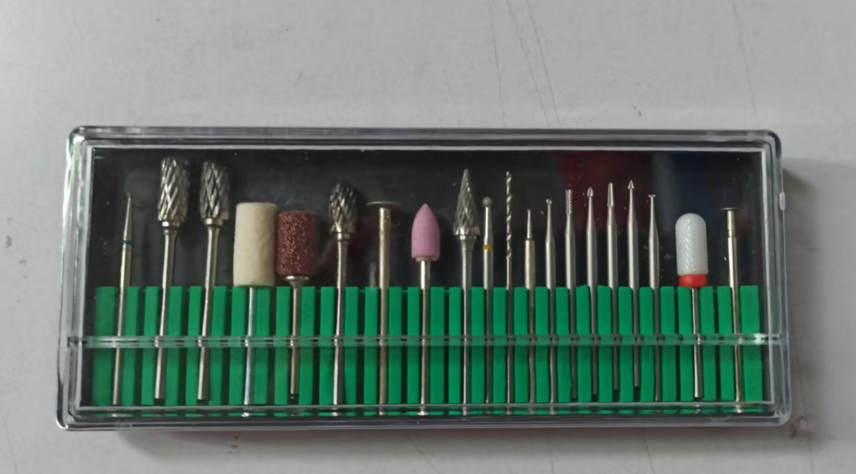 A clear plastic case holds various metal drill bits and sanding tips, organized in a green tray.