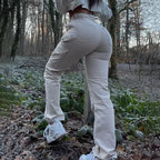 Woman wearing high-waisted beige cargo workwear pants with side pockets in a forest setting.