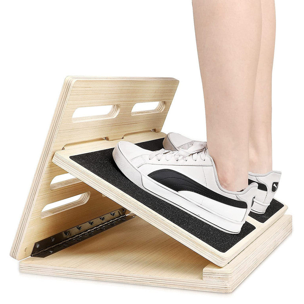 Adjustable wooden slant board for stretching with a black non-slip surface and metal hinges, isolated on white.