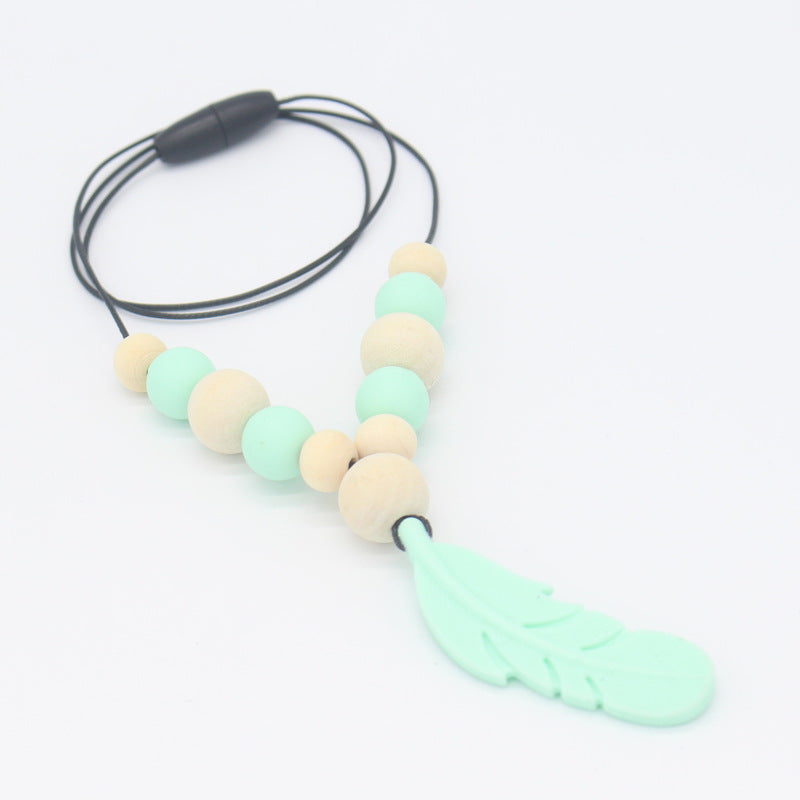 Baby teether necklace with mint silicone feather charm, wood beads, and a black cord on a white background.
