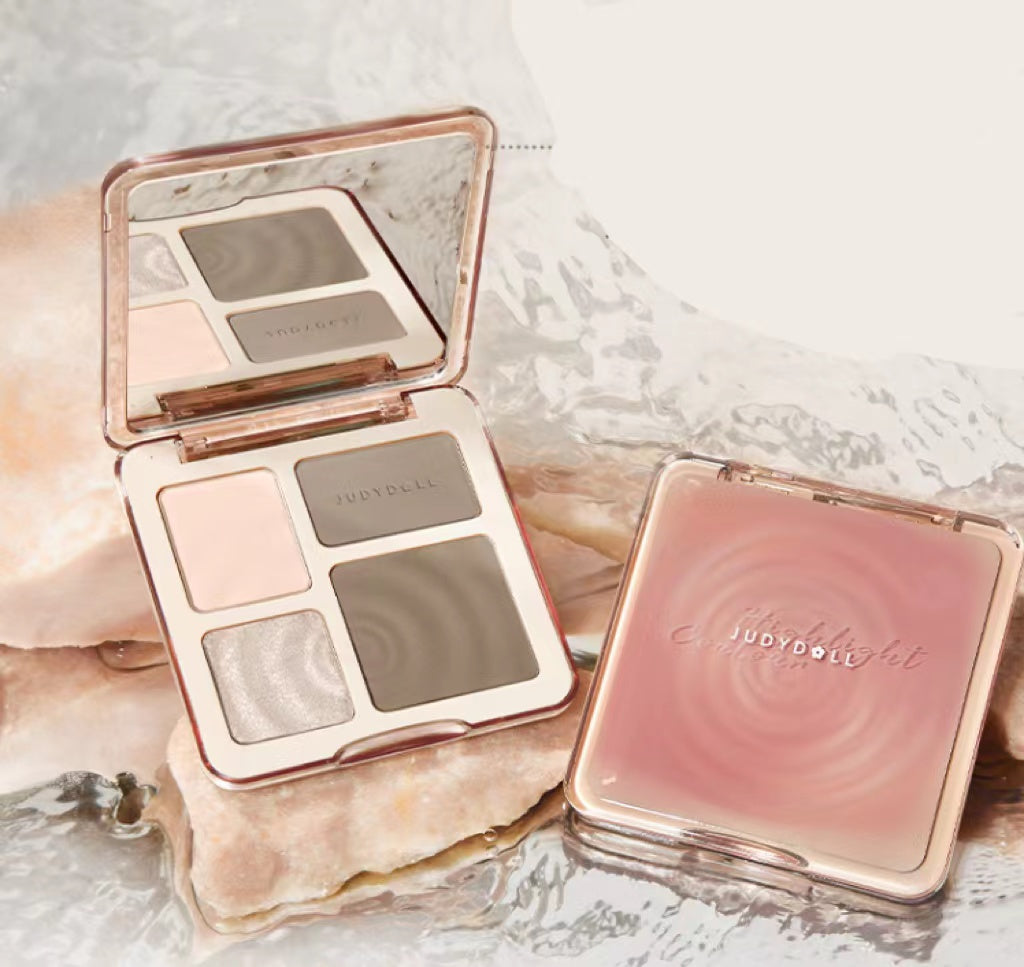 Judydoll highlight and contour palette with three matte and shimmer shades, open and closed, on a reflective surface.