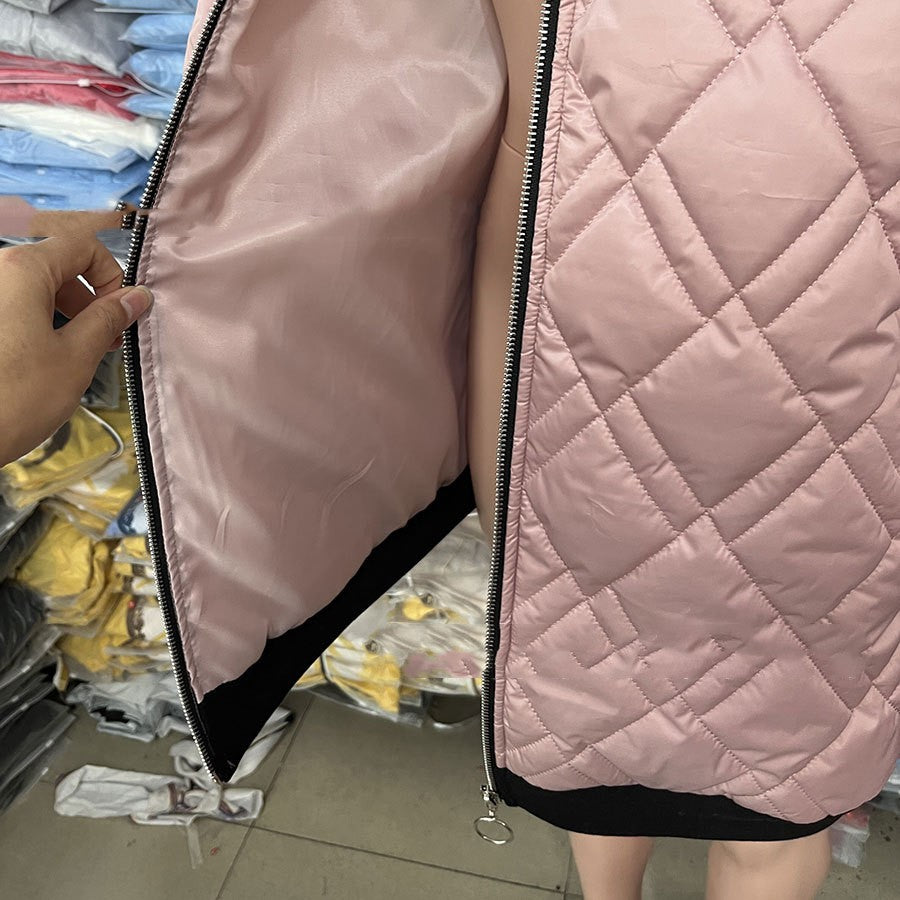 A close-up of a pink, quilted, zip-up puffer vest with a smooth, matching interior lining and a black bottom hem.