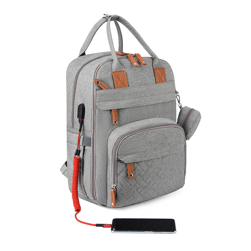 Grey fabric stroller backpack with brown leather accents, external USB charging cable, and phone on white background.