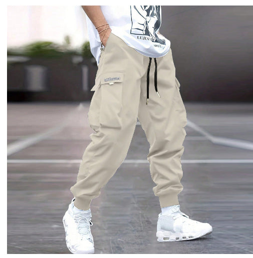 Beige cargo joggers with drawstring waist, side flap pockets, and cuffed ankles, styled for casual streetwear.