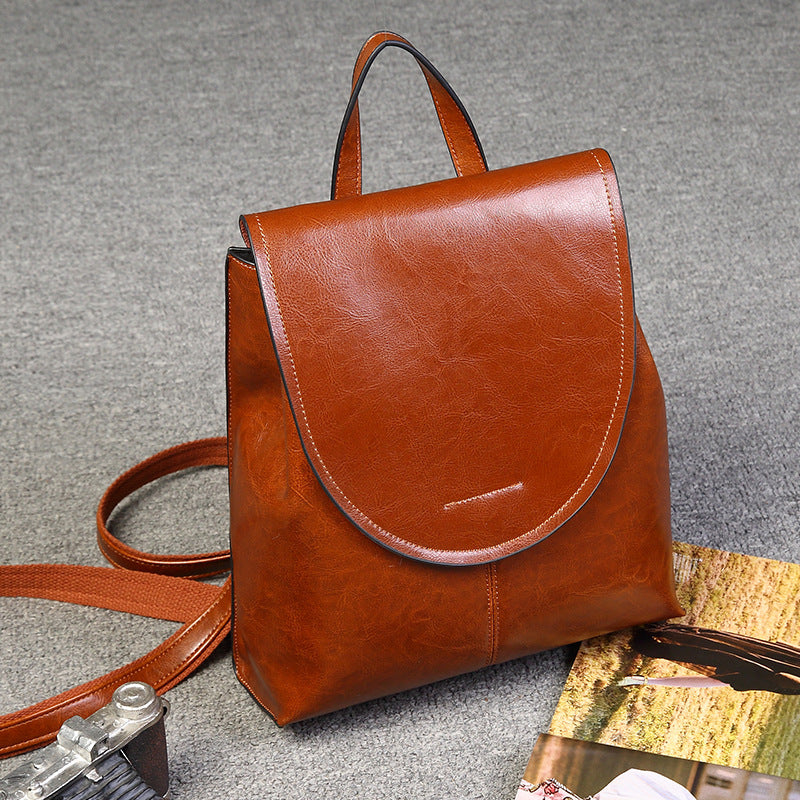 Brown leather retro-style women's backpack with a top handle, fold-over flap, and adjustable shoulder straps.