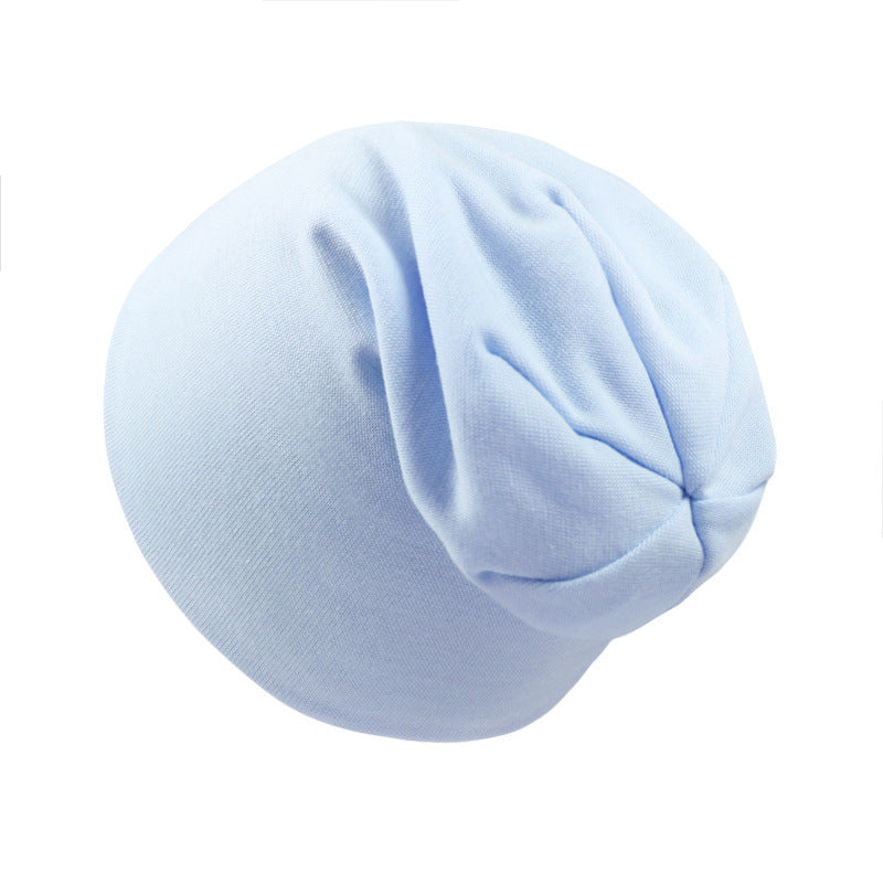 A plain, light blue newborn beanie made of soft, stretchy knit fabric with a gathered top design.