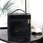 Glossy black, boxy, large-capacity makeup bag with a top handle, gold heart-shaped zippers, and embossed logo.