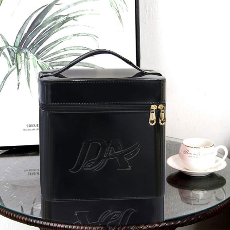 Glossy black, boxy, large-capacity makeup bag with a top handle, gold heart-shaped zippers, and embossed logo.
