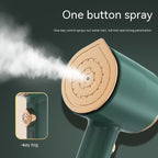 Dark green portable garment steamer with a gold-toned iron plate emitting steam and a single steam button.