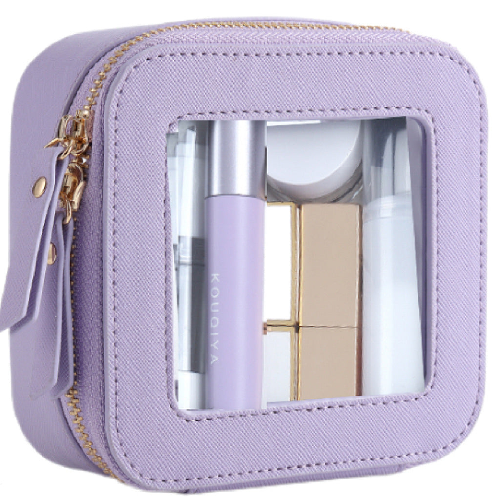 Small square purple PU leather cosmetic bag with a transparent window, gold zipper, and filled with makeup products.