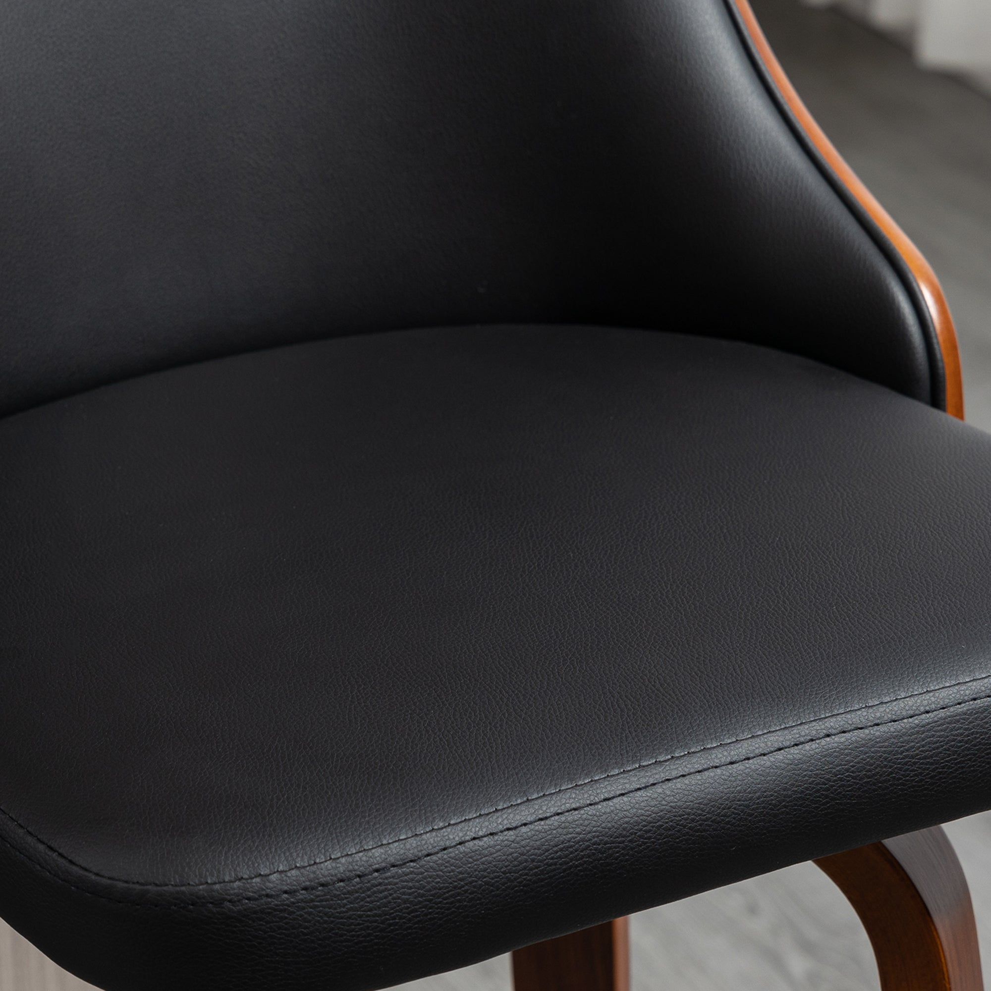 Black faux leather bar stool with a curved, walnut-finished wood frame and backrest. Close-up shot.