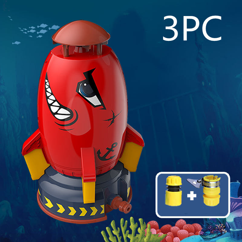 Red, shark-themed rocket water sprinkler toy with yellow fins, base, and two included hose attachments.