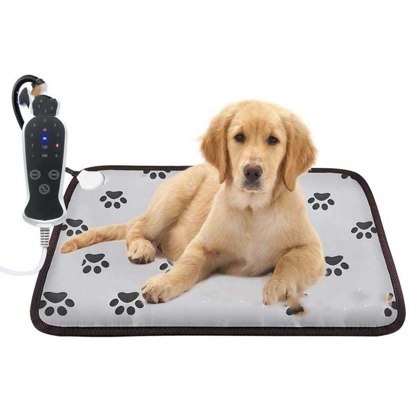 Golden puppy lying on a gray waterproof pet heating pad with paw print patterns and a digital temperature controller.