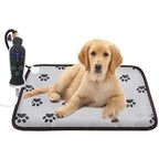 Golden puppy lying on a gray waterproof pet heating pad with paw print patterns and a digital temperature controller.
