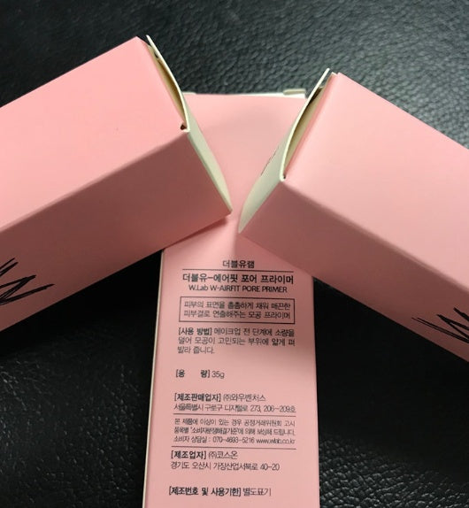 Two matte pink W.Lab Airfit Pore Primer boxes with Korean text on a dark, textured surface.