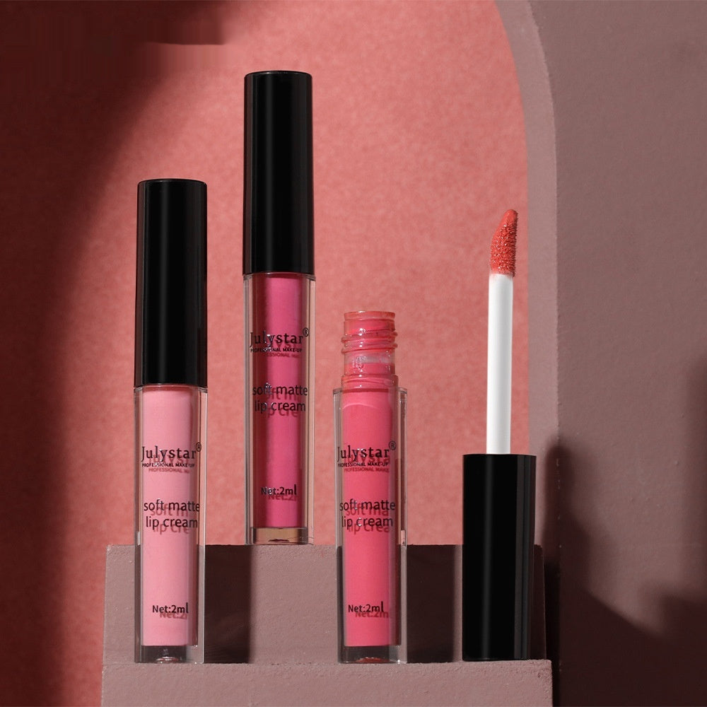 Three Julystar matte lip cream tubes in various pink shades on a tiered stand, one open with a wand applicator.