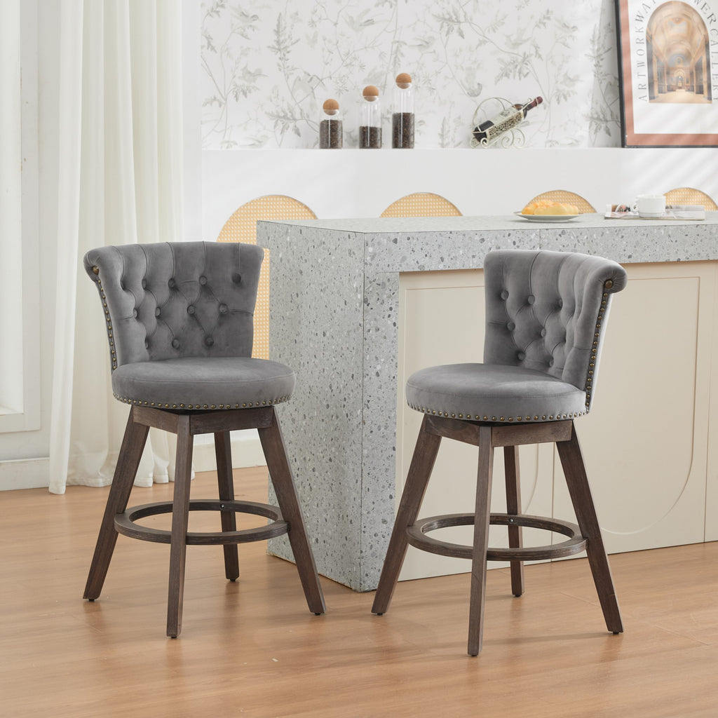 Set of 2 gray tufted velvet swivel bar stools with nailhead trim and brown wood legs in a modern kitchen.