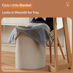 Grey plush foot warmer blanket draped over a textured beige cylindrical office stool under a desk.