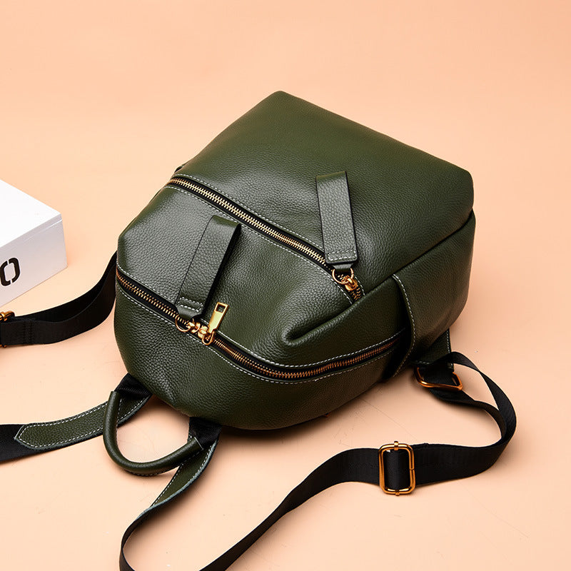 Small olive green top-layer leather backpack with gold zippers, black fabric straps, and a soft pebble-grain texture.