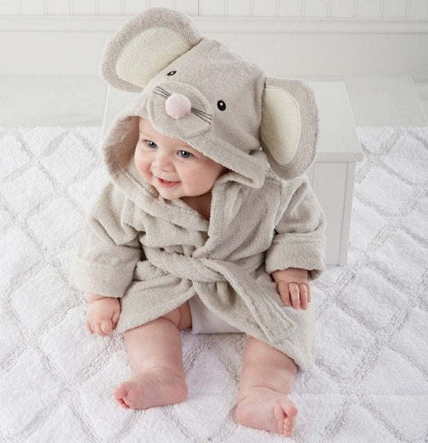 A cute baby wearing a soft, beige cotton hooded bathrobe with mouse ears and a pink nose on a white textured mat.
