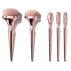Drunk Gold makeup brush set: five pieces with metallic rose-gold handles and soft, light pink synthetic bristles.