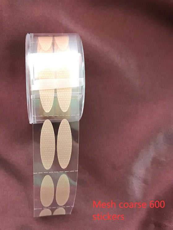 A roll of 600 beige, oval, mesh-textured eyelid stickers on a clear adhesive strip for creating double eyelids.